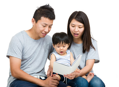 家庭成员爸爸摄影照片_对年轻的夫妇看书的男婴