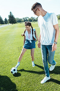 体育生摄影照片_快乐的少年男孩和女孩在公园玩足球