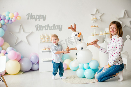在孩子们的聚会上，一个带着气球和蛋糕的金发碧眼的小男孩在生日那天很可爱。孩子们的派对气球；气球