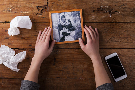 love摄影照片_Unrecognizable sad woman holding broken picture of couple in love.