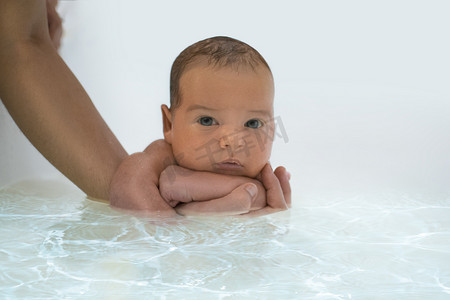 初生婴儿第一次和父母的手帮助一起游泳。婴儿的新生儿黄疸。把重点放在婴儿头上