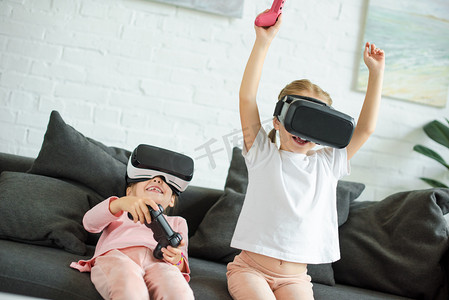 玩1摄影照片_模糊的视野中的孩子在虚拟现实耳机在家里的沙发上玩视频游戏