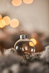 在雪地里的云杉树枝上挂着透明的圣诞球，灯亮着
