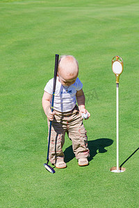 开车可爱摄影照片_可爱的小宝宝的男孩，在一个字段上打高尔夫球