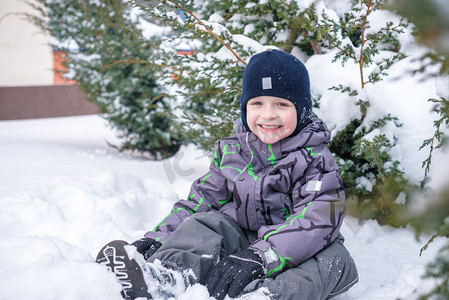 冬天的孩子男孩穿着五颜六色的服装，在户外在降雪的画像。积极的休闲活动，跟在冷的下雪天的孩子。快乐的孩子玩雪