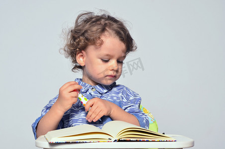 学习如何写和读的蹒跚学步。小小孩玩乐学校准备和在一本书上绘图.