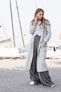 灰色休闲裤摄影照片_美丽迷人的魅力女孩摆姿势站在时尚的时尚现代的外观.