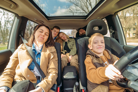 开车可爱摄影照片_汽车旅行有趣的概念。小男孩开车与成年人的人。不自信的驱动程序