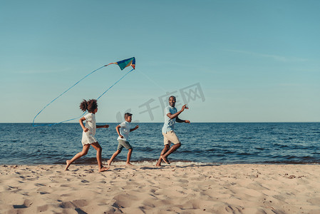 父亲和孩子们在海滩上玩风筝