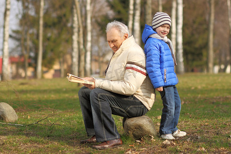 dziadek i wnuczek, czytając książkę na zewnątrz