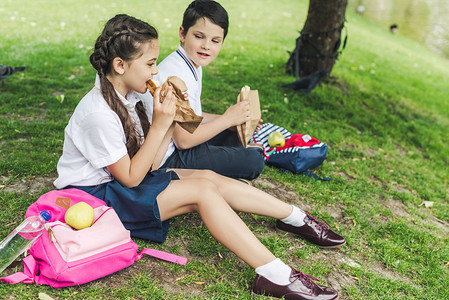 小学生坐在绿草上吃午饭