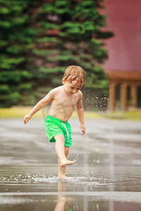 男孩玩在下大雨的水坑里的水