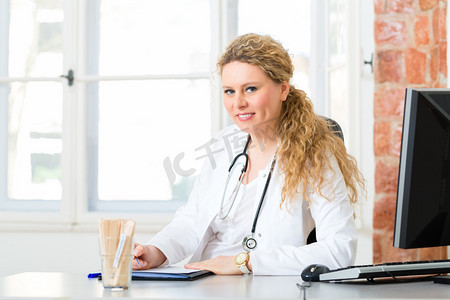 在诊所办公桌上写文档的女医生
