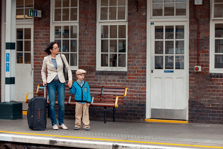 年轻的母亲和儿子在等火车铁路站场