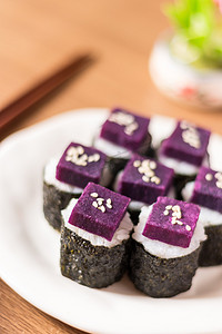寿司-紫甘薯在寿司米白色的陶瓷板。紫心甘薯的好处是高 β-胡萝卜素和用于烹饪的碳水化合物。关闭
