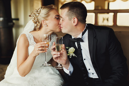 新娘和新郎吻控股酒杯香槟在他们