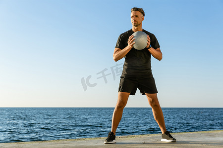 英俊的成年运动员在海边健身球