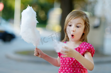 可爱的小女孩在户外吃棉花糖