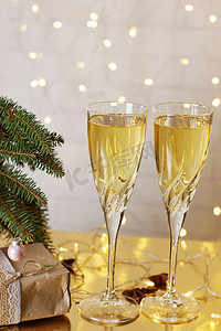 圣诞树旁边的桌子上有两杯香槟酒.