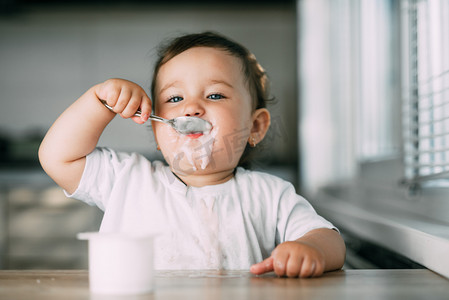 自己好摄影照片_一个迷人的小女孩吃酸奶都涂抹自己