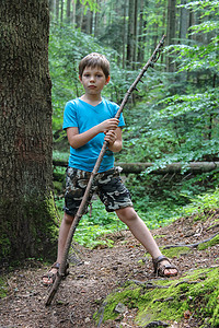 男孩用长长的木头棍子在森林公园