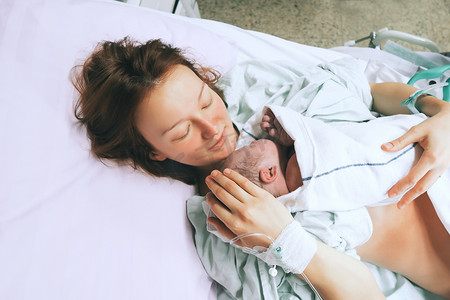 妈妈抱着她刚出生的婴儿在医院分娩后. 