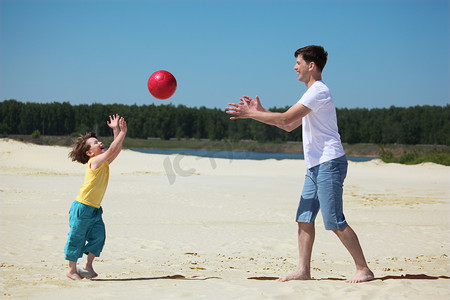 红色开心摄影照片_儿子对父亲的沙子上抛球