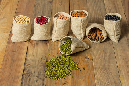 不同种类的豆子和桂皮中的木制背景上塑袋