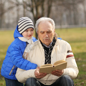春天摄影照片_dziadek i wnuczek, czytając książkę na zewnątrz