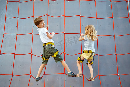 女孩抱男孩摄影照片_Little boy and girl  in  rock climbing gym