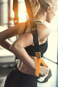培训室摄影照片_金发碧眼的健身女人培训 trx 健身肩带