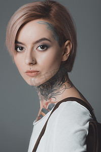纹身肖像摄影照片_美丽的年轻女子的肖像与纹身看在灰色隔离摄像头