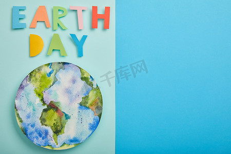 蓝色纸质背景摄影照片_五颜六色的纸质信件和行星图片的顶视图在绿色和蓝色背景, 地球天概念