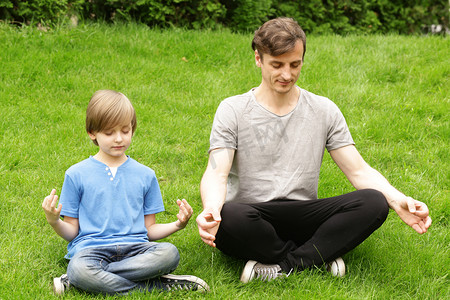 父亲和儿子坐在绿草和冥想