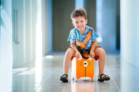 快乐之旅摄影照片_可爱快乐的孩子带着手提箱在机场
