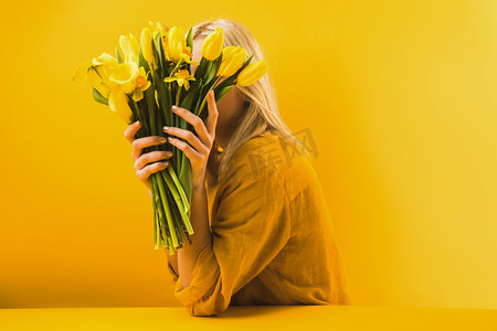 国际罕见病日摄影照片_在黄色的年轻妇女藏品美丽的黄色春天花 