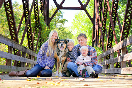 四人和狗坐在桥上，在秋天的家庭