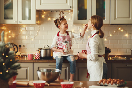 吃帽子摄影照片_快乐的家庭母亲和孩子们烘焙圣诞饼干