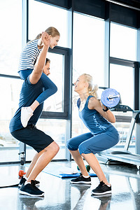 体育培训班摄影照片_而男子玩女儿扛在肩上的杠铃女人锻炼