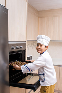 亚洲的中国男孩在白色厨师均匀烘烤饼干