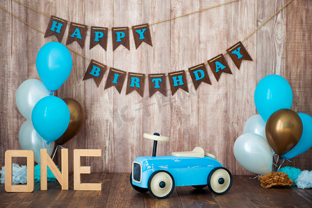 玩具车摄影照片_蓝色复古玩具车与氦气球在木背景上。儿童假日装饰的照片区为一个小男孩。生日快乐, 1年.