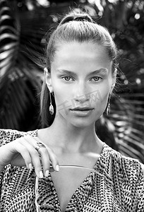 时尚fashion摄影照片_Portrait of beautiful fashion woman in tropics with black sunglasses. Sexy girl wearing color overalls, stylish earrings and ring poses on island.