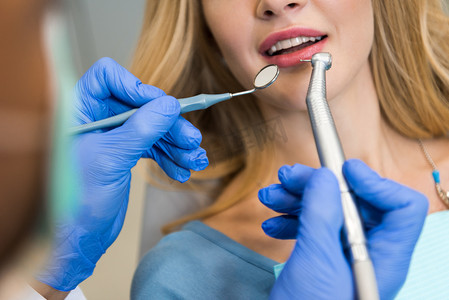 裁剪拍摄的牙医检查牙齿的女性客户