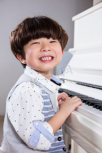 快乐亚洲中国小男孩在家里弹钢琴