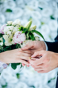 玫瑰摄影照片_新郎把结婚戒指放在手指上的裁剪视图 