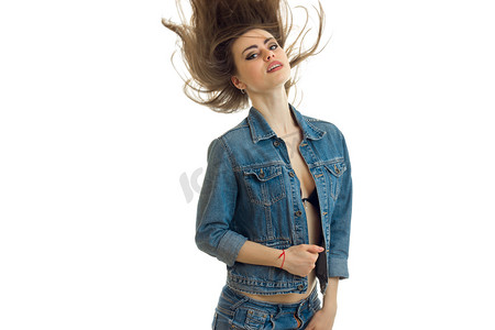 年轻漂亮的女孩在牛仔裤夹克构成对相机和她的头发在空中飞翔