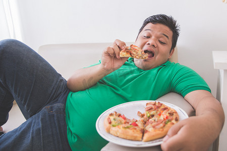 而躺在沙发上懒超重的人，吃披萨
