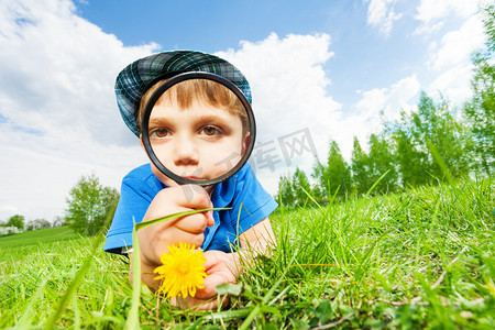 Small boy with magnifier and yellow flower