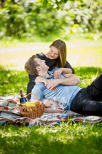 可爱的女人拥抱男友在野餐毯子上的肖像