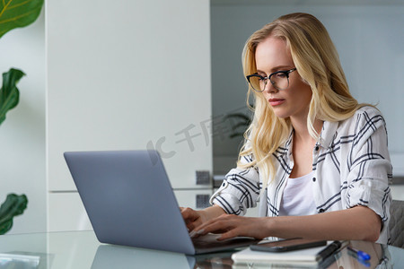 在家工作时使用膝上型电脑的年轻金发女郎